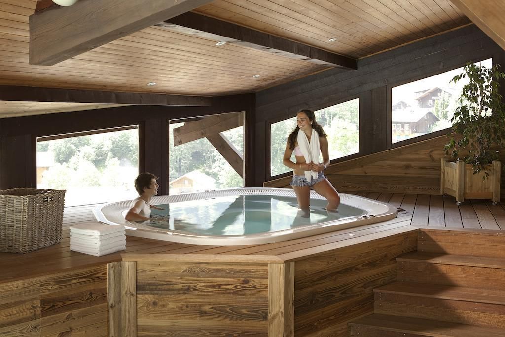 Een houten interieur met een jacuzzi, grote ramen en uitzicht op het landschap.