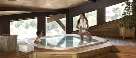 Un interior de madera con una bañera de hidromasaje, ventanas amplias y vistas al exterior.