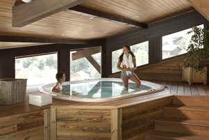 Un interior de madera con una bañera de hidromasaje, ventanas amplias y vistas al exterior.