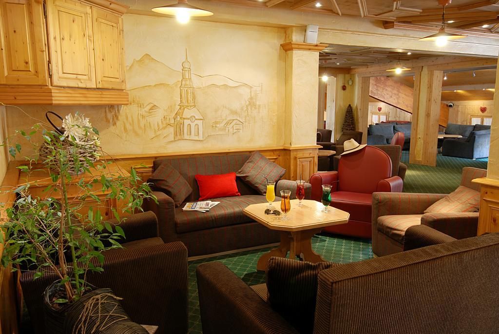 A cozy lounge area with a sofa, armchairs, a small table with drinks, and a wall mural.
