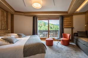 A hotel room with a bed, a sofa, a small table, and a view of the outdoors.