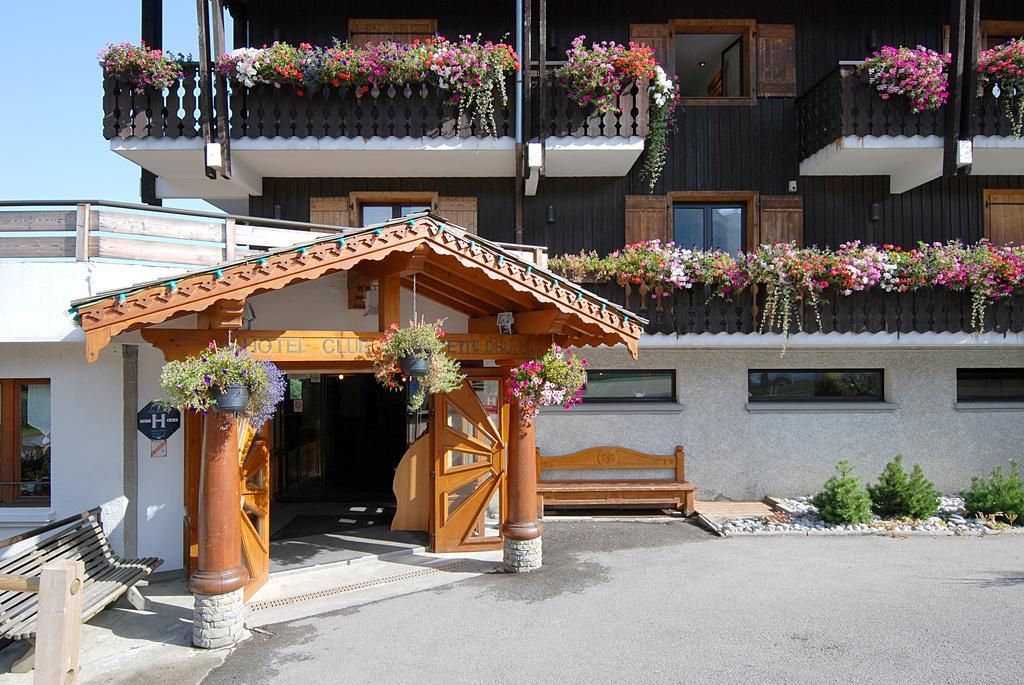 L’entrée d’un hôtel, avec une arche en bois, un banc et des jardinières sur les balcons.