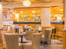 A bar area with seating and a bar counter stocked with bottles.