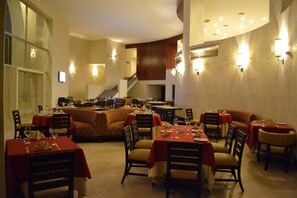 A restaurant with multiple dining areas, including a central seating area with a curved bench and several tables with chairs. - Sun Hotel (Santa Cruz)
