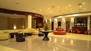 A spacious lobby with a curved reception desk, multiple seating areas, and a bar.