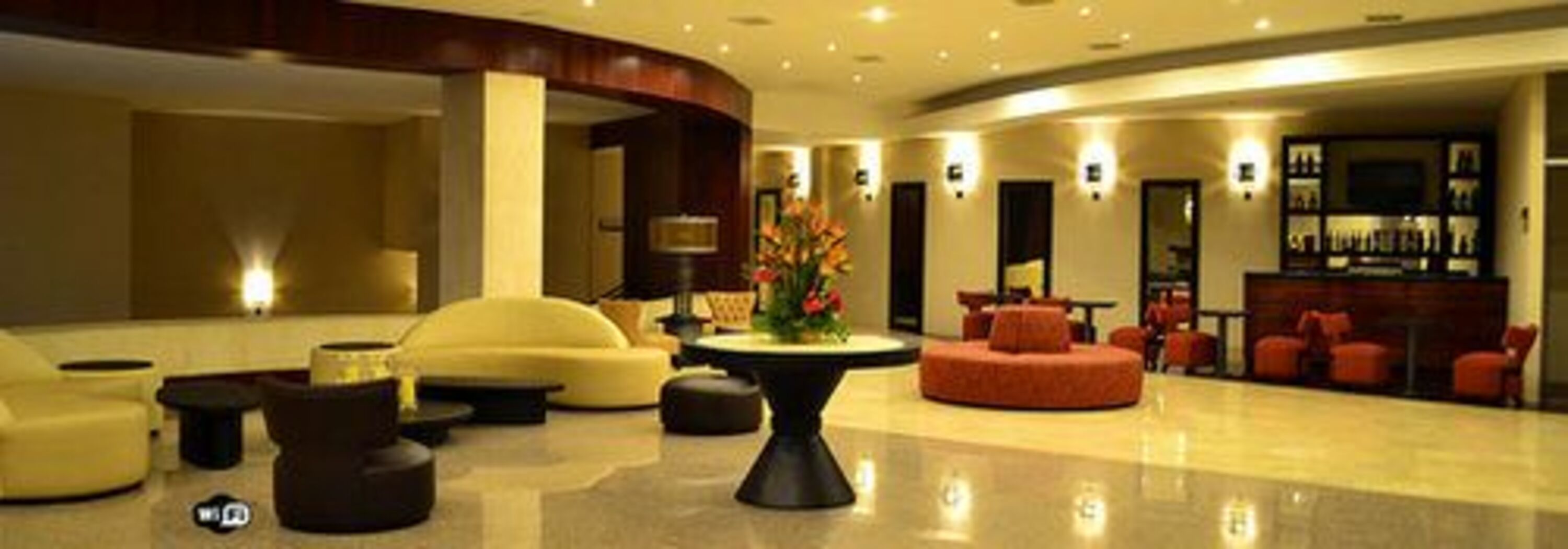 A modern lobby with a curved seating area, a central table, and a bar with shelves.