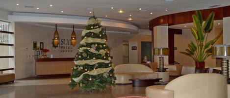 A lobby with a Christmas tree, leather sofas, and a reception desk.