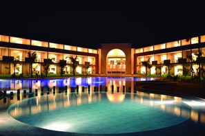 A hotel with a large swimming pool, multiple balconies, and a central arched entrance. - Sun Hotel (Santa Cruz)