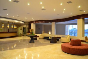 A spacious lobby with a reception desk, seating areas, and large windows offering views. - Sun Hotel (Santa Cruz)
