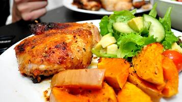 A plate with grilled chicken, roasted sweet potatoes, and a side salad.