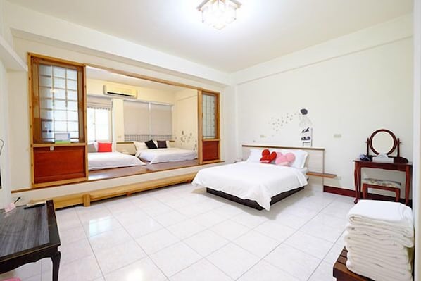 Una habitación de hotel con un espejo grande, una cama con ropa de cama blanca, una mesita de noche y una silla.
