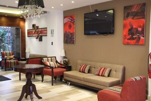 Una sala de estar moderna con sofá, sillones, una mesa de centro y obras de arte en las paredes.