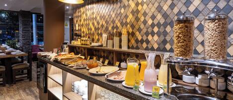 Un buffet de petit-déjeuner proposant une variété d’aliments, un coin café et un bar à jus de fruits.