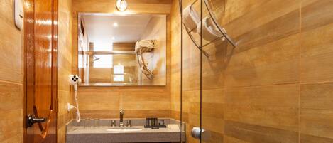 A modern bathroom with wooden walls, a glass shower enclosure, a white toilet, and a vanity with a mirror.