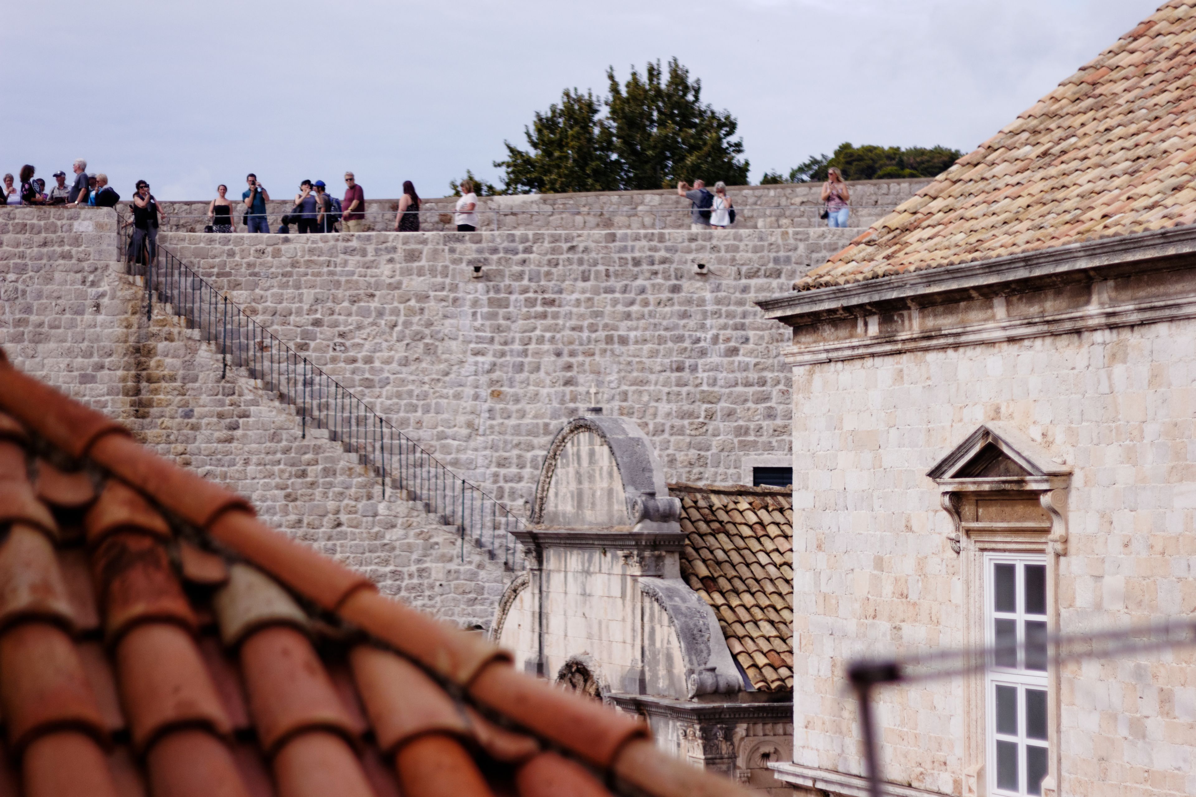 A stone staircase leading up to a stone wall with people on top.