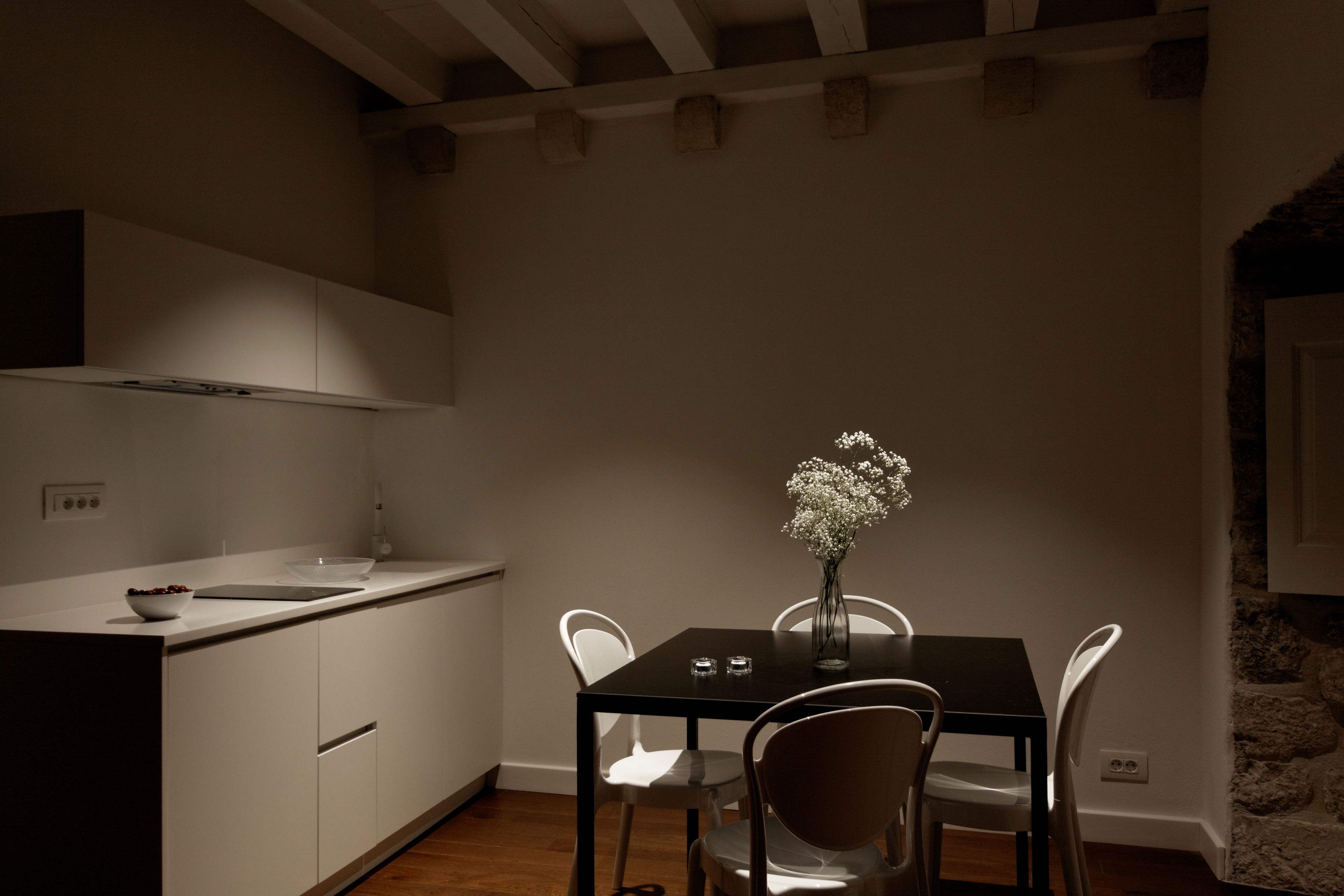 Uma cozinha moderna com armários brancos, uma mesa de jantar preta e cadeiras brancas.