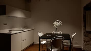 Uma cozinha moderna com armários brancos, uma mesa de jantar preta e cadeiras brancas.
