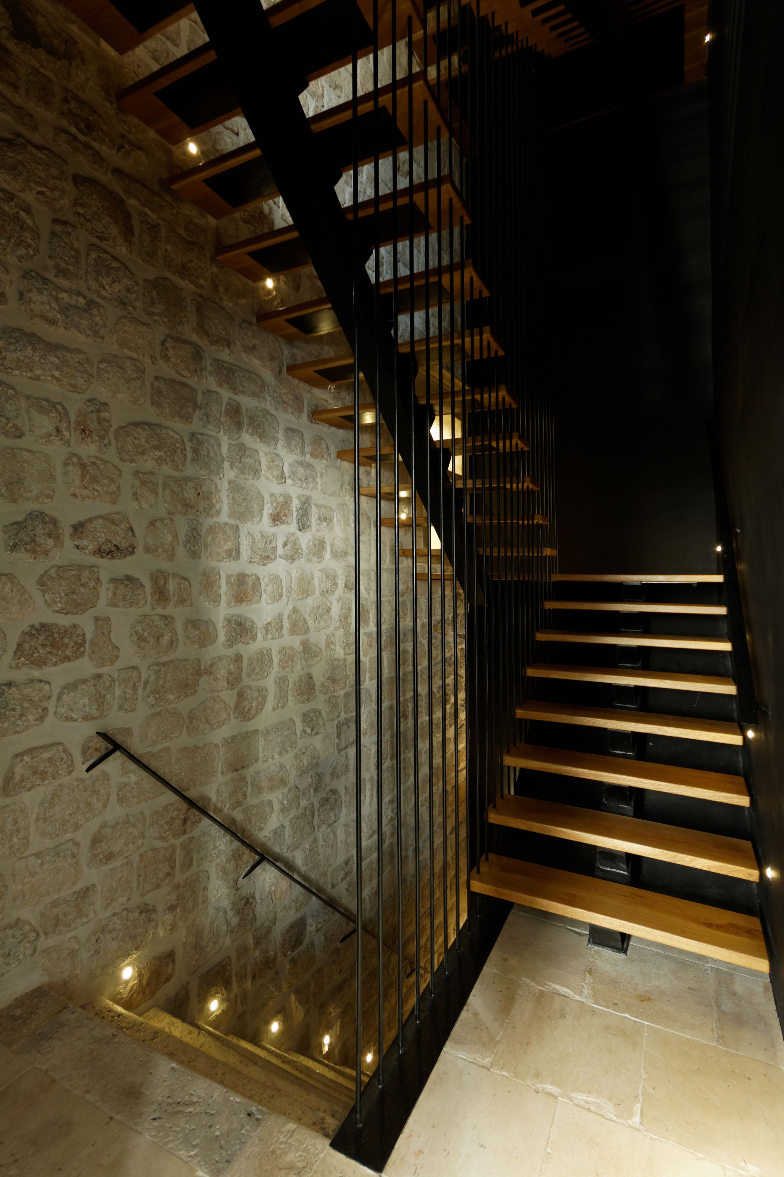 Eine Treppe mit Steinwänden und Holzboden, die zu einer höheren Etage führt.