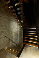 A staircase with stone walls and wooden steps, leading to a higher floor.