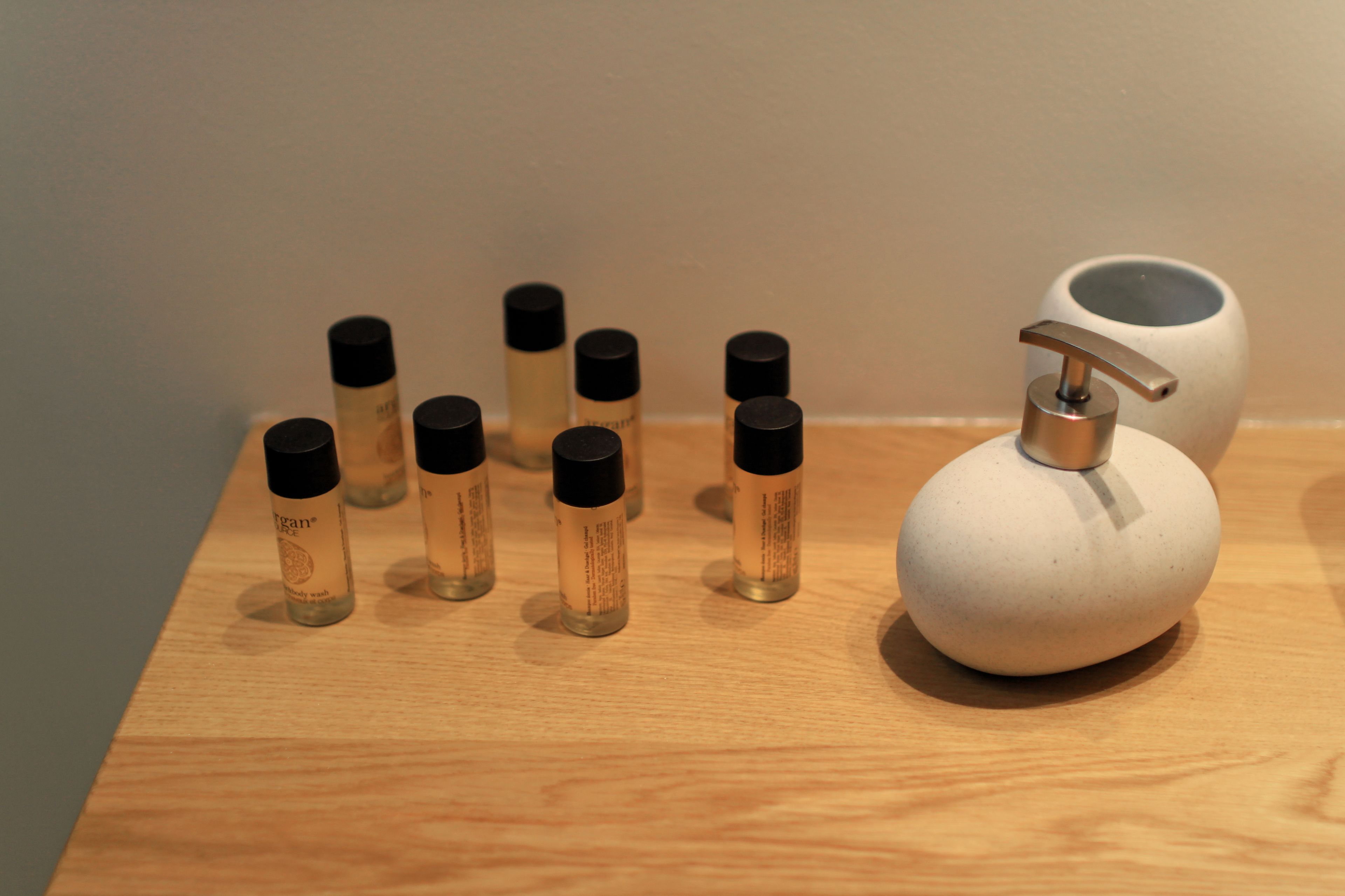A wooden surface with several small bottles and a pump dispenser.
