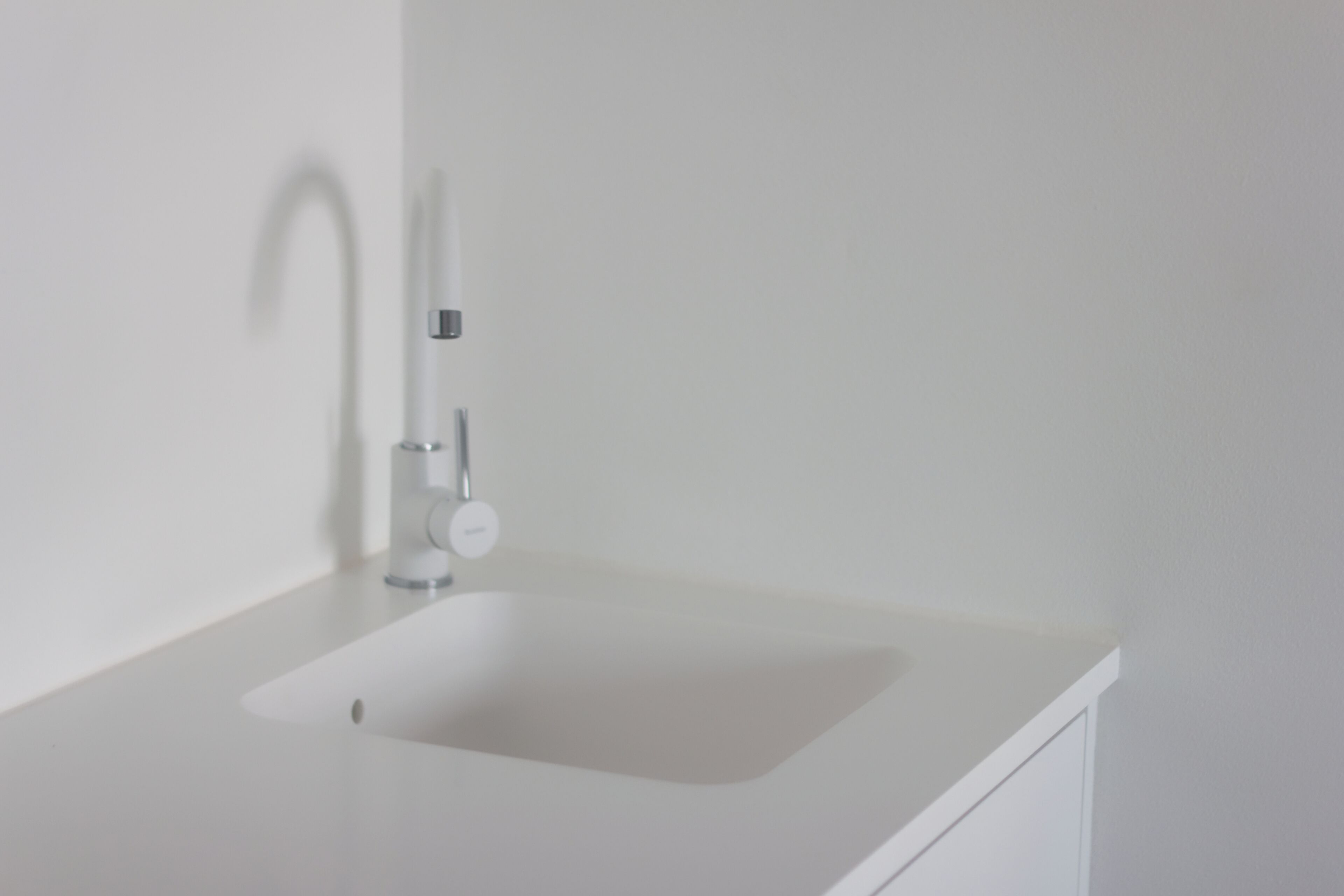 A white bathroom sink with a modern faucet and a single drawer below.