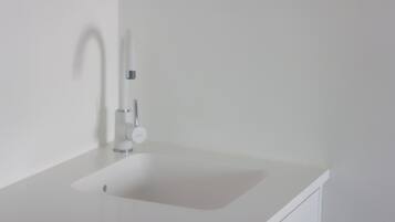 A white bathroom sink with a modern faucet and a single drawer below.