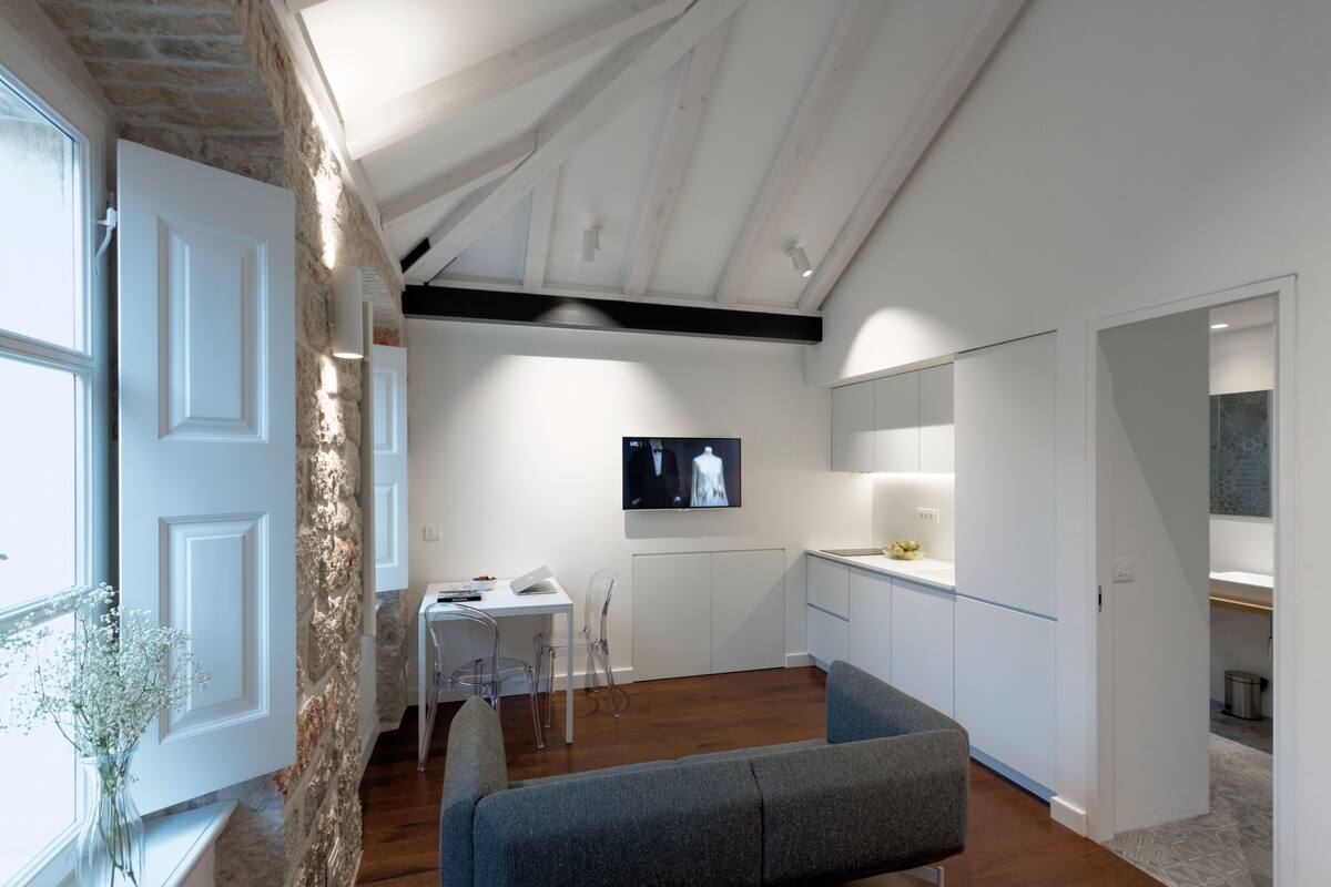 A modern interior with a stone wall, a dining area, a kitchen, and a living space with a sofa.