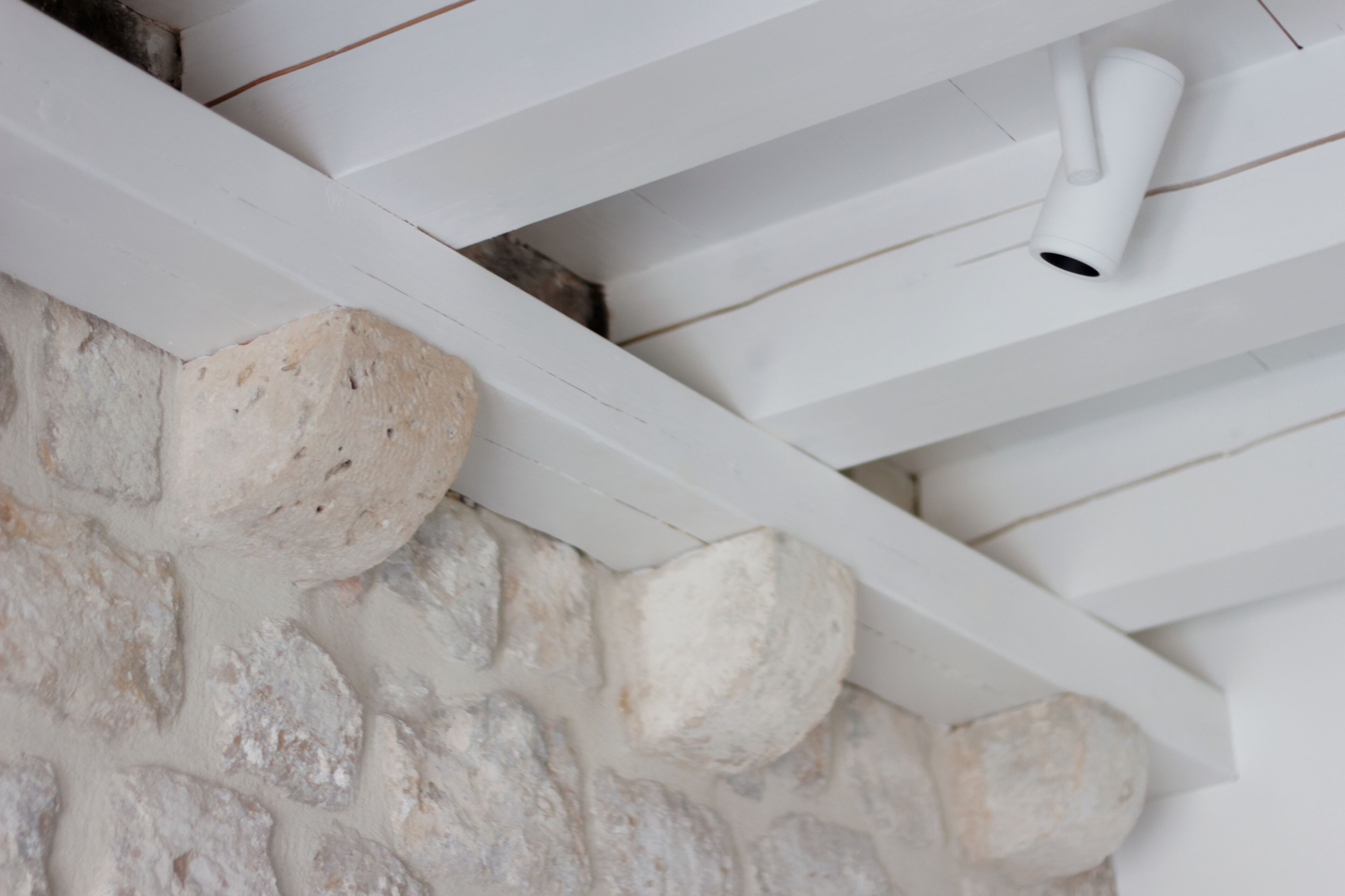 Un plafond blanc, un mur en pierre et un ventilateur de plafond blanc.