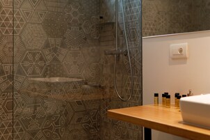 Um banheiro com paredes estampadas, um aparador de madeira e área de chuveiro.