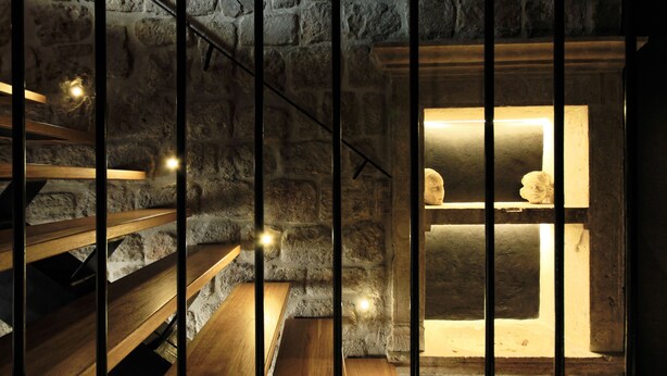 A stone-walled room with a wooden bench and a small window with a statue. - Apartments Eleganca (Dubrovnik)