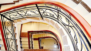 A grand staircase with ornate metal railings and a curved design, leading to an upper level. - Marie's Royale Hotel (Kampala)