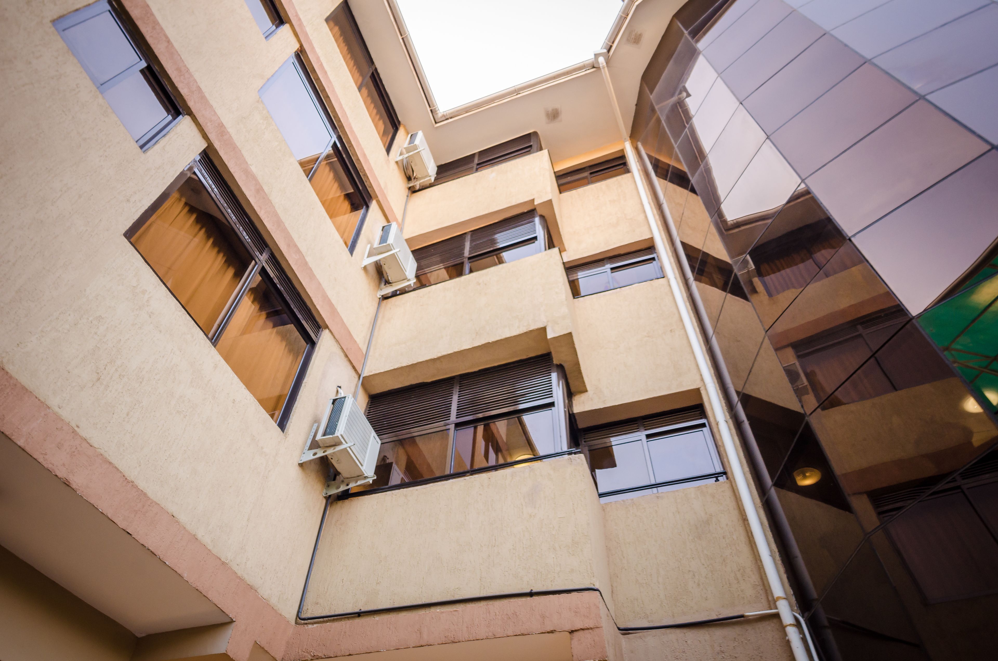 A multi-story building with balconies, air conditioning units, and a modern architectural design.