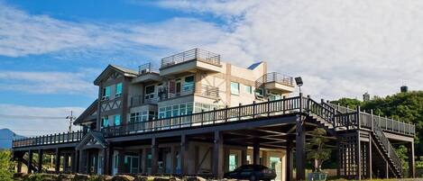 Un edificio de varios pisos con una terraza de madera y escaleras que conducen a un balcón.