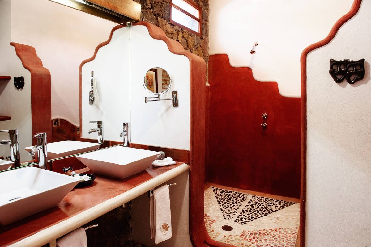 Een badkamer met twee wastafels, een spiegel en een douchecabine.