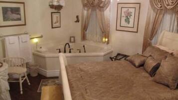 Une chambre avec un grand lit, une baignoire, une chaise et une petite table.
