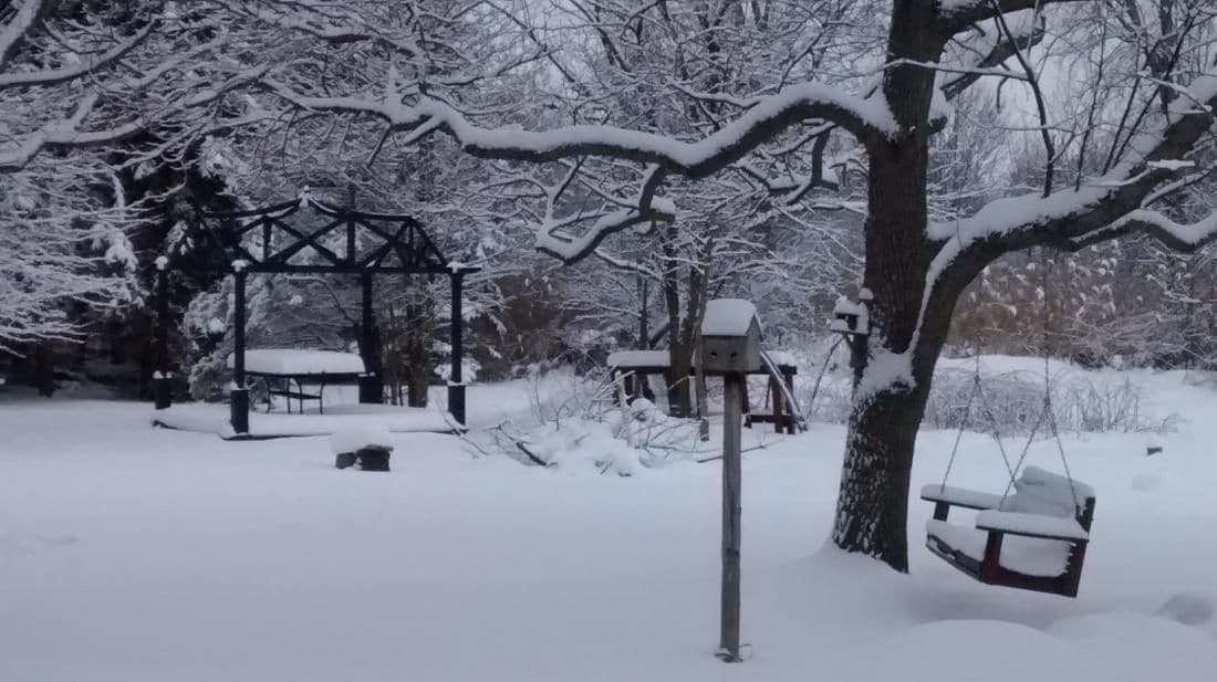 Een park bedekt met sneeuw, met een schommel en een houten constructie.