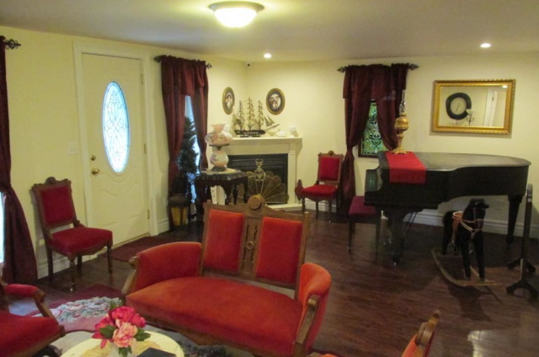 A living room with a red sofa, a piano, and a fireplace.
