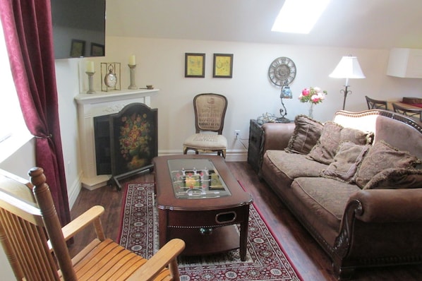 A cozy living room with a fireplace, a sofa, a coffee table, and a chair. - The Lost Pearl (Madison)