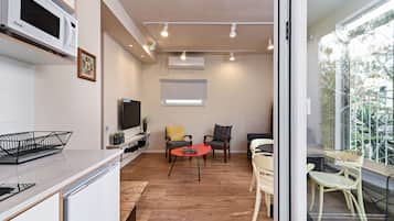 A modern kitchen with a microwave, a dining area with a red table, and a seating area with chairs.