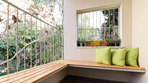 A corner bench with a window overlooking a garden. - Hanasi 129 - Boutique Apartments (Haifa)