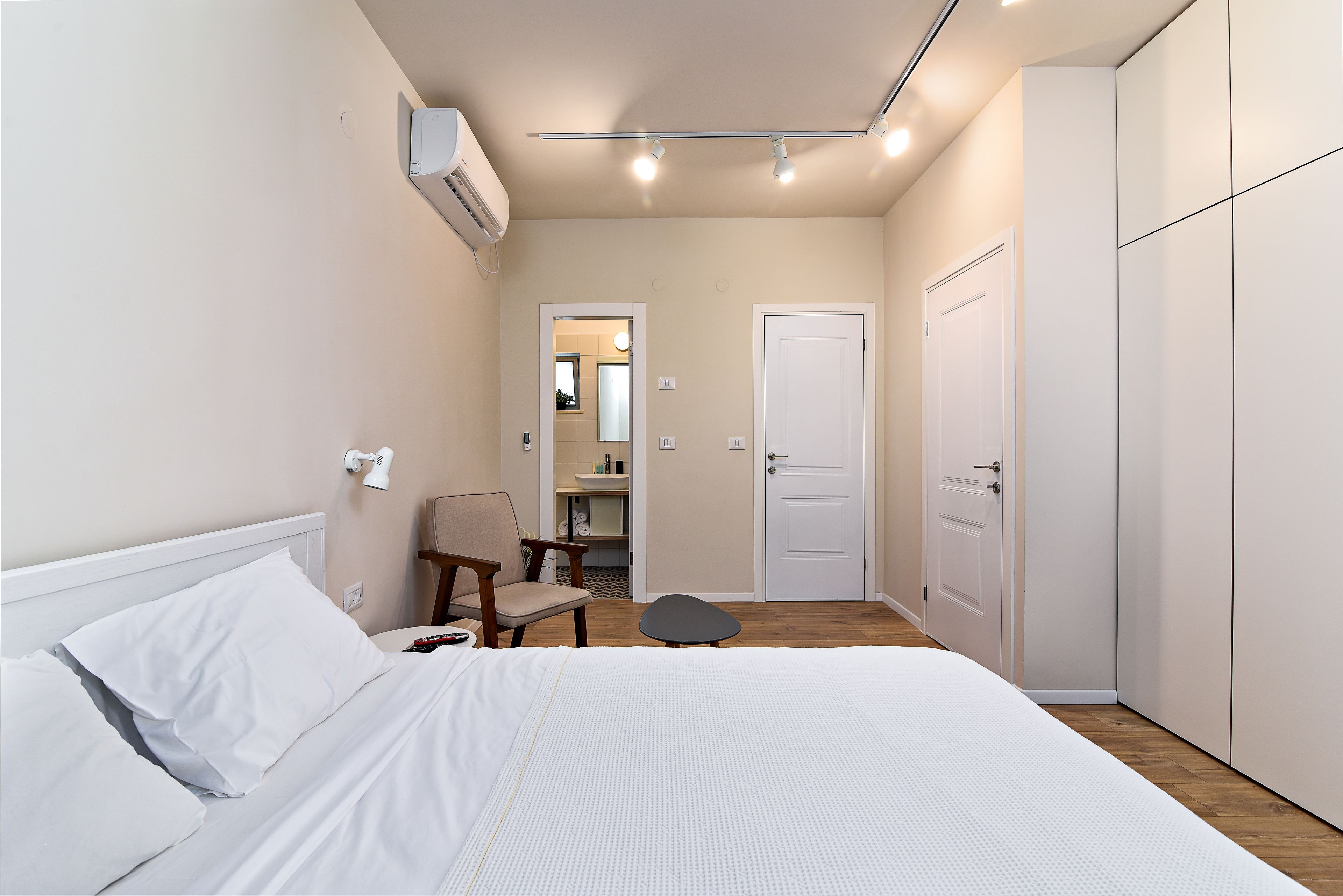 A bedroom with a bed, a chair, a desk, and a wardrobe.