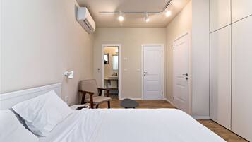 A bedroom with a bed, a chair, a desk, and a wardrobe.