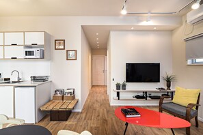 A modern apartment with a kitchen, dining area, and living room. It includes a TV, a red table, and a sofa.