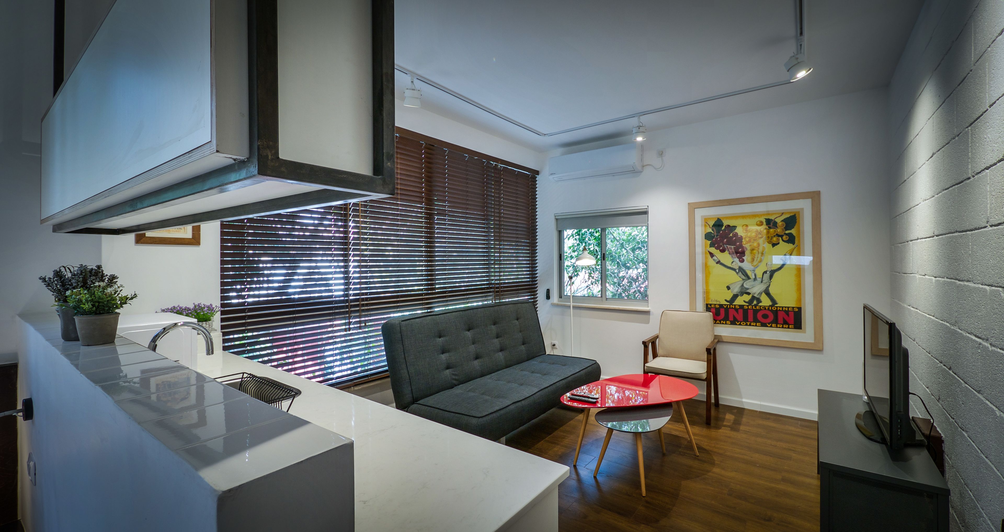 Une cuisine moderne avec une cuisinière intégrée, un canapé gris et une table rouge.