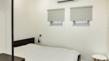 A bedroom with a bed, bedside table, and a small round table.