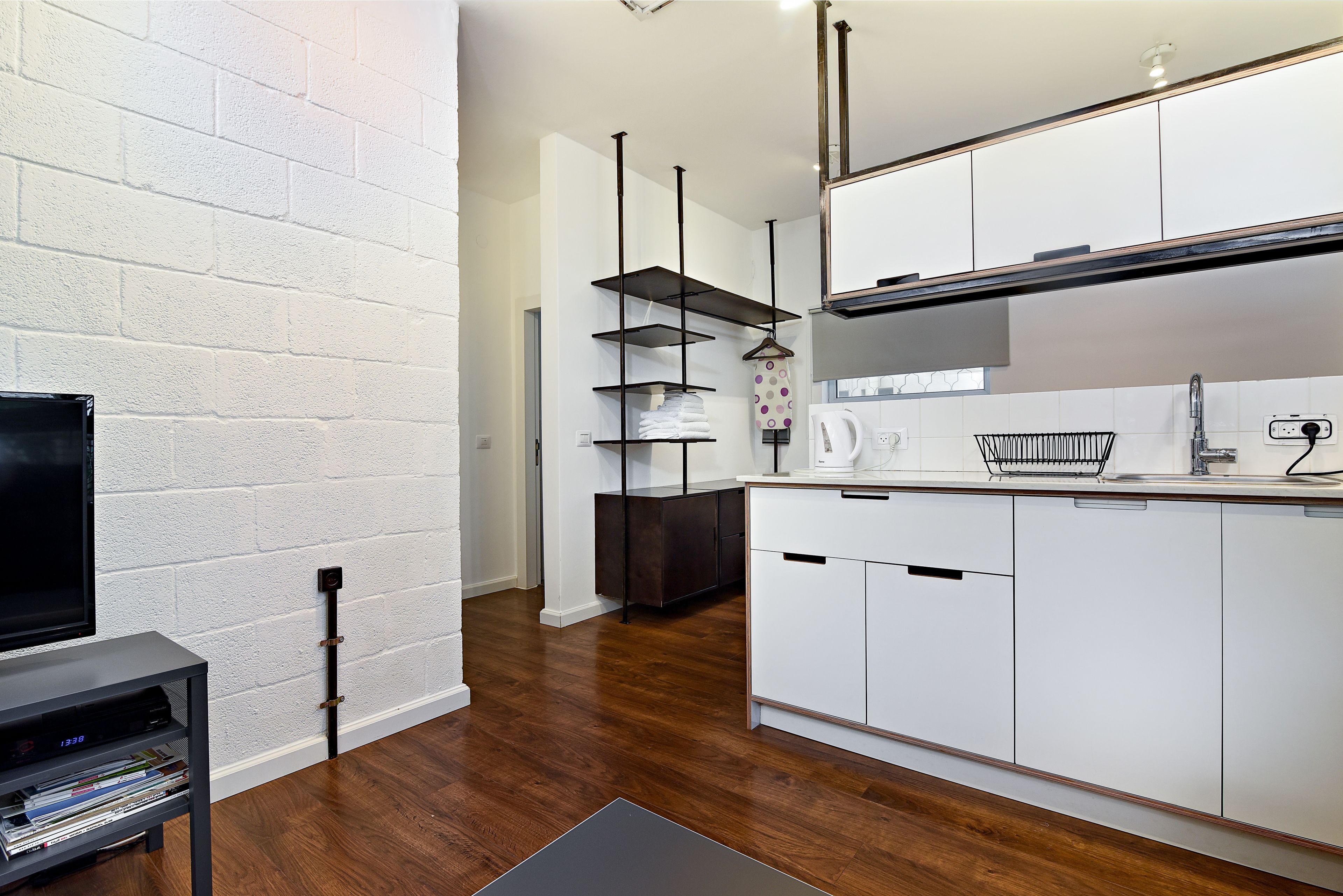 Una cocina moderna con armarios blancos, encimera negra y un perchero para toallas.