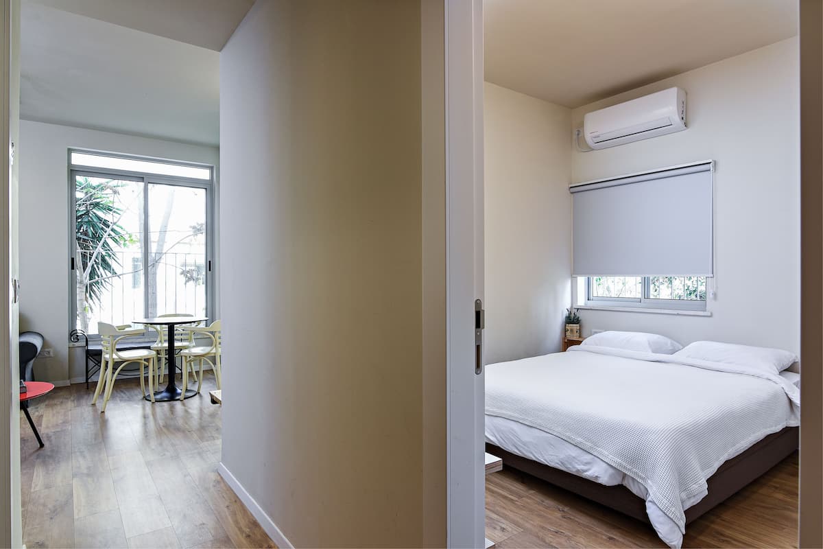 Une chambre avec un lit, un appareil de climatisation, une fenêtre et un coin repas comprenant des chaises et une table.