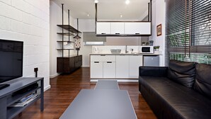 A modern living room with a flat-screen TV, a black leather sofa, and a coffee table. - Hanasi 129 - Boutique Apartments (Haifa)