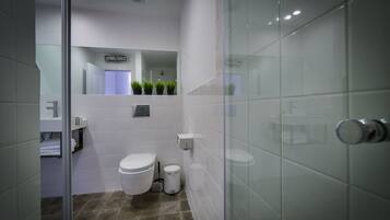 Un baño moderno con inodoro, bidé y cabina de ducha de vidrio.