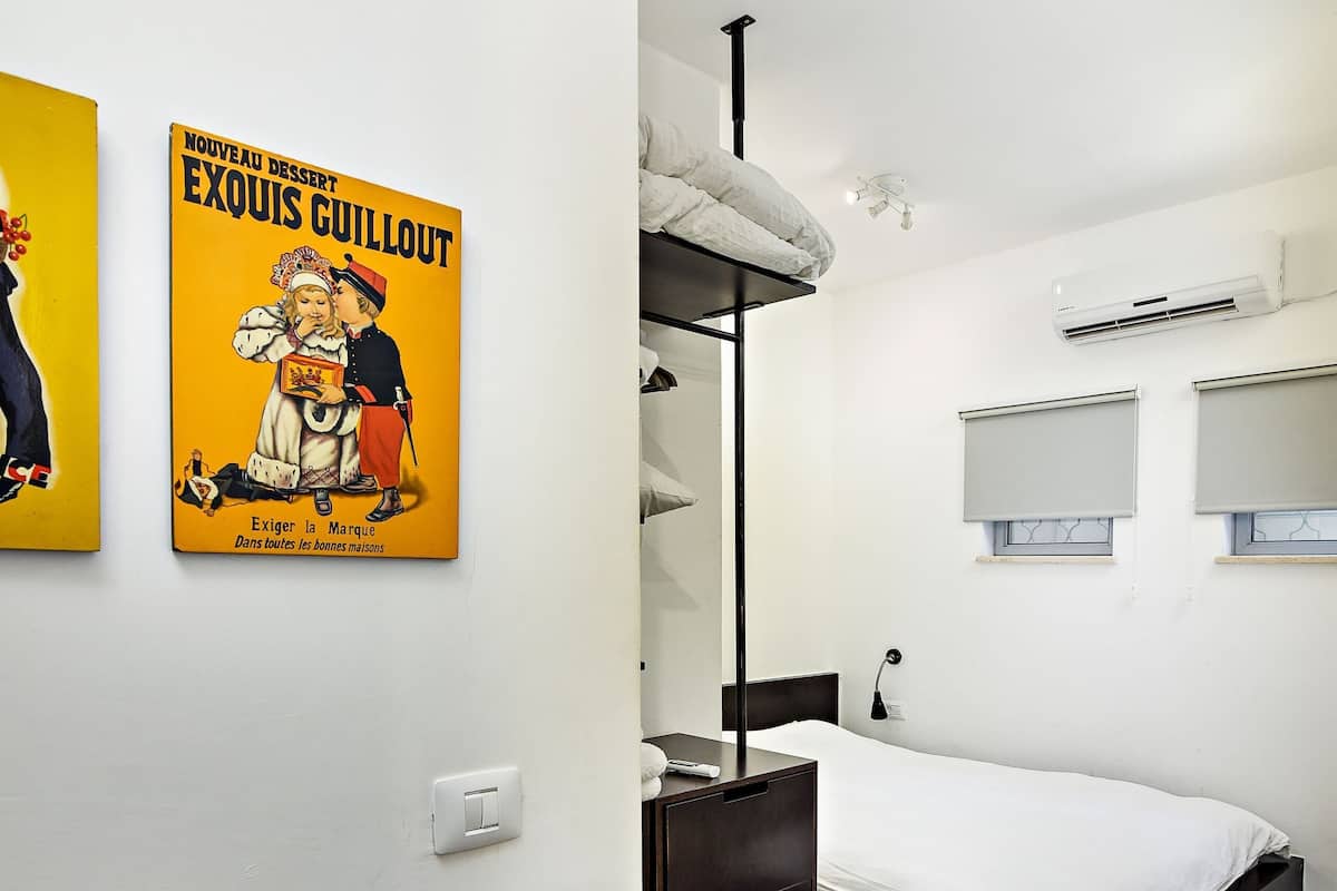 Une chambre moderne avec un lit, une table de chevet, une lampe suspendue et un climatiseur fixé au mur.
